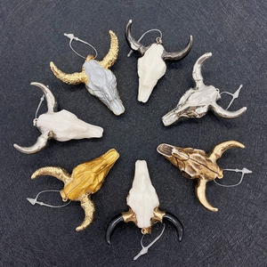 Cow skull pendants in various colors with metallic horns on a black background