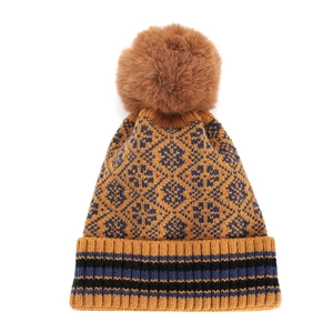 Winter beanie with geometric diamond pattern and brown faux fur pom-pom in mustard yellow