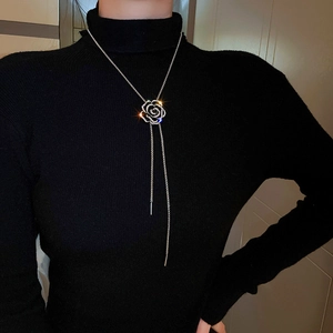 Detailed view of silver camellia necklace with sparkling zircon and long tassel pendant