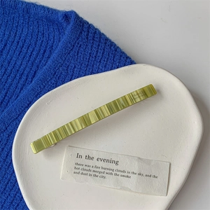 Close-up of green resin hair clip with wavy texture and France Handmade text on ceramic