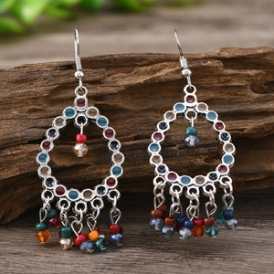 Vintage Indian style bell tassel earrings with colorful beads on a rustic wood background