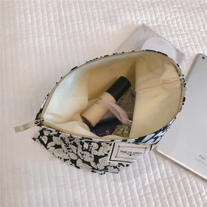 Macro view of floral canvas makeup bag with metal zipper and TIME TO PARTY woven label