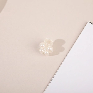 Macro view of a mini pearl flower hair claw clip with cream white beads on a warm base