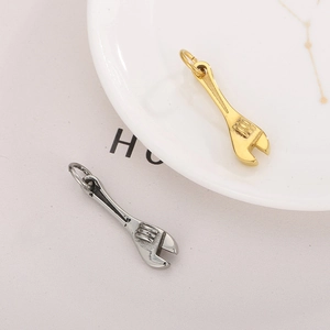 Detail of creative stainless steel wrench pendants in gold and silver on a ceramic tray