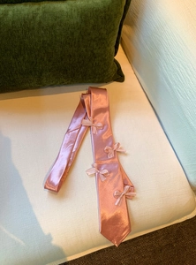 Detail shot of the elegant pink satin bow tie necklace featuring delicate ribbon bows
