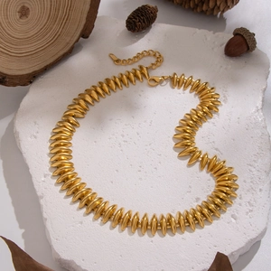 Exaggerated golden stainless steel bullet link necklace on a rustic natural stone background
