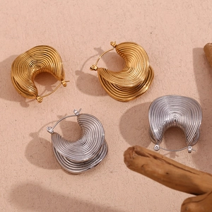 Macro shot of 18K gold and silver plated earrings with textured ribbed metal patterns