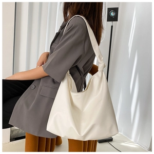 Model wearing large off-white leather tote bag with knotted shoulder strap detail
