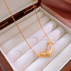 Close-up of golden whale pendant with matte finish and tiny zircon on O-chain