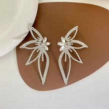 Detail of silver wing stud earrings with sparkling rhinestones on textured background