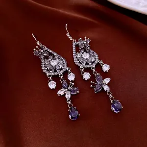 Elegant silver butterfly earrings with purple zircon floral drops on silk background