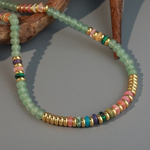 Handmade beaded necklace with natural colorful stones and gold spacers on a wooden branch