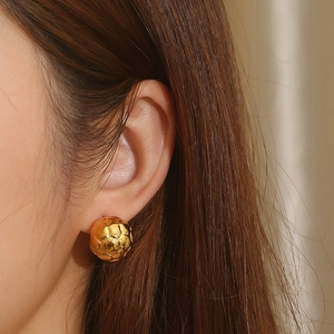 Golden football textured ball stud earrings in stainless steel on female model