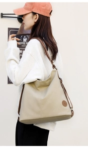 Dettaglio della borsa tote beige minimalista con tracolla marrone e logo in pelle