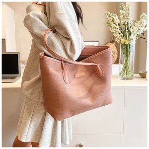 Pink woven tote bag shown on model in a cozy indoor setting with lifestyle elements