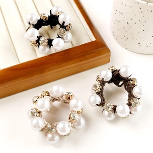 Detailed shot of three elegant pearl and rhinestone hair ties in black, beige, and brown