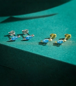 Détail macro de boucles d'oreilles dinosaure en argent S925 avec pierres marquises bleues
