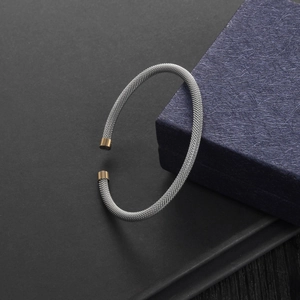 Macro view of silver mesh woven cable bracelet with elegant gold tone metal end caps