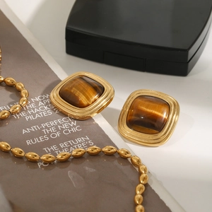 Macro view of square tiger eye stone earrings and golden bead necklace on a magazine