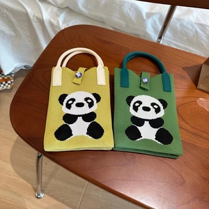 Vue à plat de sacs panda en tricot vert avec texture crochetée sur une table en bois