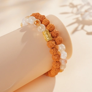 Macro shot of brown Bodhi seeds and amber crystal beads with gold cylinder charm detail