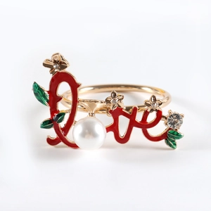 Detailed view of a gold napkin ring with red Love design, white pearl, and rhinestone