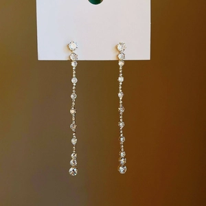 Elegant gold drop earrings featuring circular zirconia tassels on a white display card