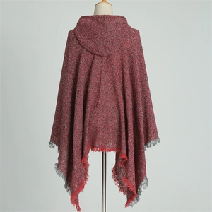 Detail view of red knitted hooded poncho with tassel fringe on a white background