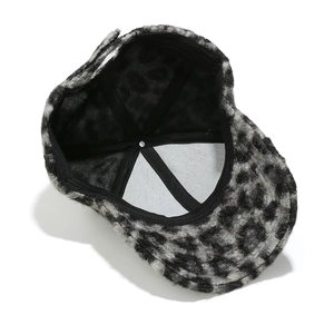 Dettaglio interno di un cappello leopardato con cinghie incrociate nere e bottone metallico