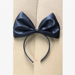 Detailed view of a black satin bow headband on a simple textured craft background