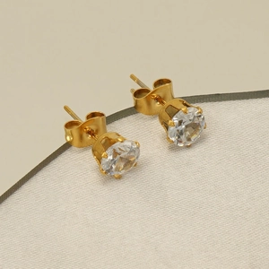 Detailed macro view of gold-tone stud earrings featuring round cubic zirconia in 6-prong setting
