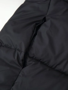 Detail of black quilted windproof fabric and hidden side pocket on hooded jacket