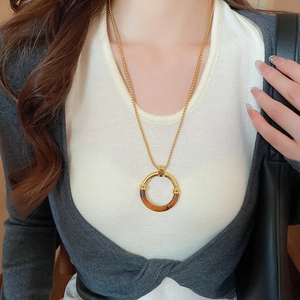Dettaglio della collana con pendente in resina dorata e motivo tartarugato su catena lunga