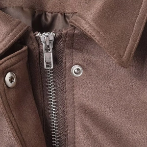 Detailed view of brown suede jacket collar with metallic zipper and snap buttons