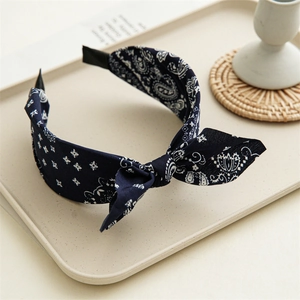 Dettaglio del cerchietto in tessuto blu scuro con motivo paisley e nodo decorativo