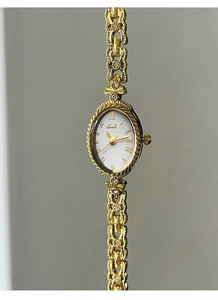 Vue détaillée d'une montre dorée ovale vintage avec cadran blanc et chiffres romains