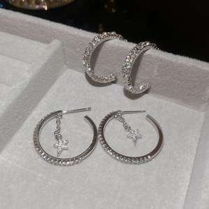 Detail of silver C-shape star stud earrings with pavé zircons in a jewelry box