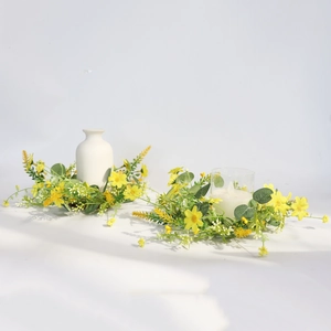 Close-up of yellow daisy and eucalyptus candle rings on ceramic vase and glass holder
