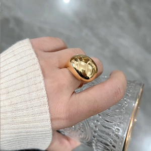 Polished gold teardrop statement ring worn on hand holding a textured glass