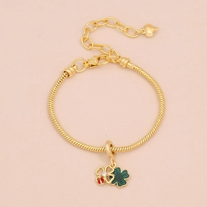 Détail d'un bracelet maille serpent doré avec breloques trèfle et coccinelle en émail