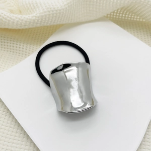 Close-up of a silver curved alloy ornament on a black elastic hair tie for low pony tails