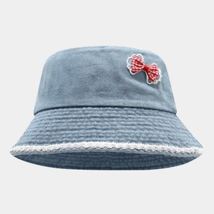Detail of light blue denim bucket hat with white lace trim and red plaid bow decoration