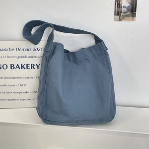 Dettaglio della borsa tote in tela di cotone blu con tracolla larga su un supporto bianco