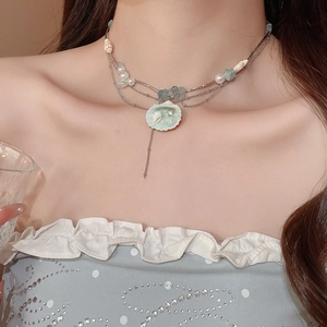 Detail of layered ocean-style necklace with shell pendant and blue stones on neck