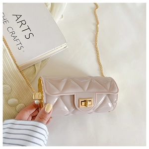 Detail of beige quilted cylindrical bag featuring gold chain and side pearl accent