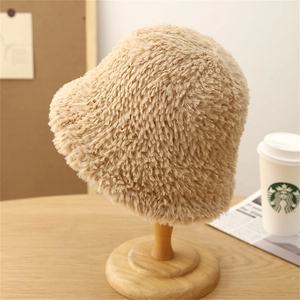 Dettaglio della texture del cappello a secchiello in peluche beige su supporto di legno