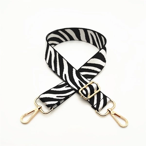 Adjustable black and white zebra pattern bag strap with gold metal hooks on white background