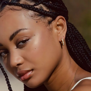 Élégantes créoles dorées avec perles blanches sur mannequin sous lumière naturelle