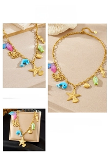 Detail of gold chain necklace with colorful enamel sea creature charms like dolphins and starfish