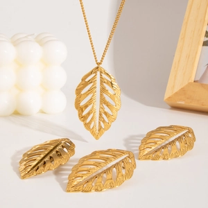 Parure de bijoux dorés avec feuilles ajourées, collier et boucles d'oreilles sur fond blanc